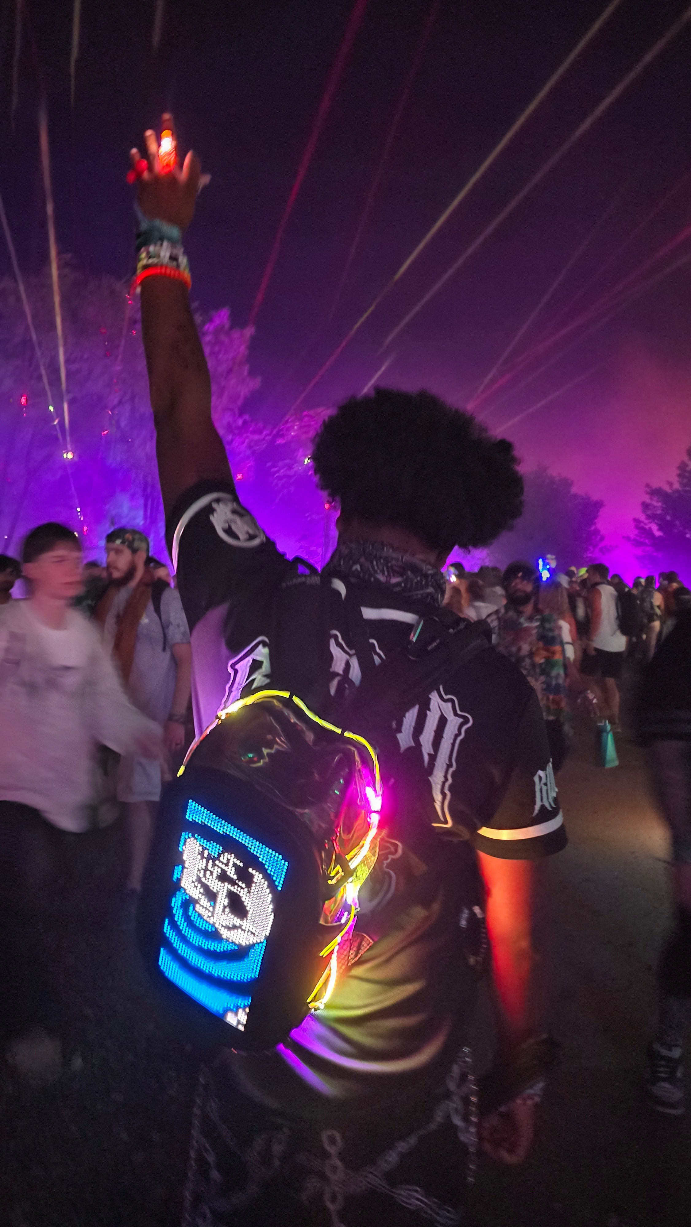 Raver with EDC hydration pack featuring app-controlled screen at night event
